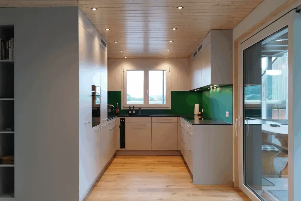 Küche in Hellgrau mit grüner Glasrückwand und Holzdecke